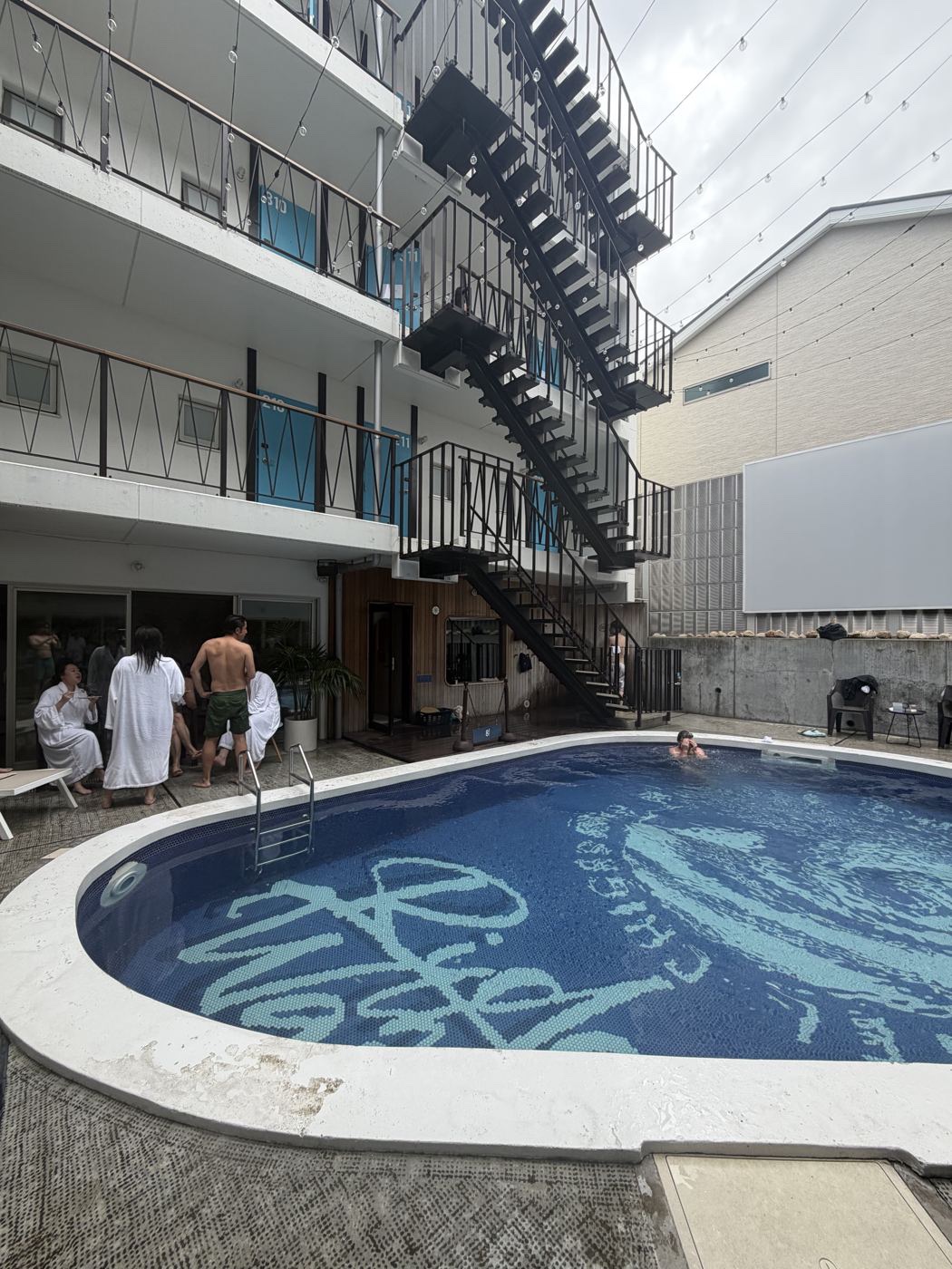 夕方の8HOTEL CHIGASAKIの中庭プール。ガウン姿のゲストがプールサイドに集う