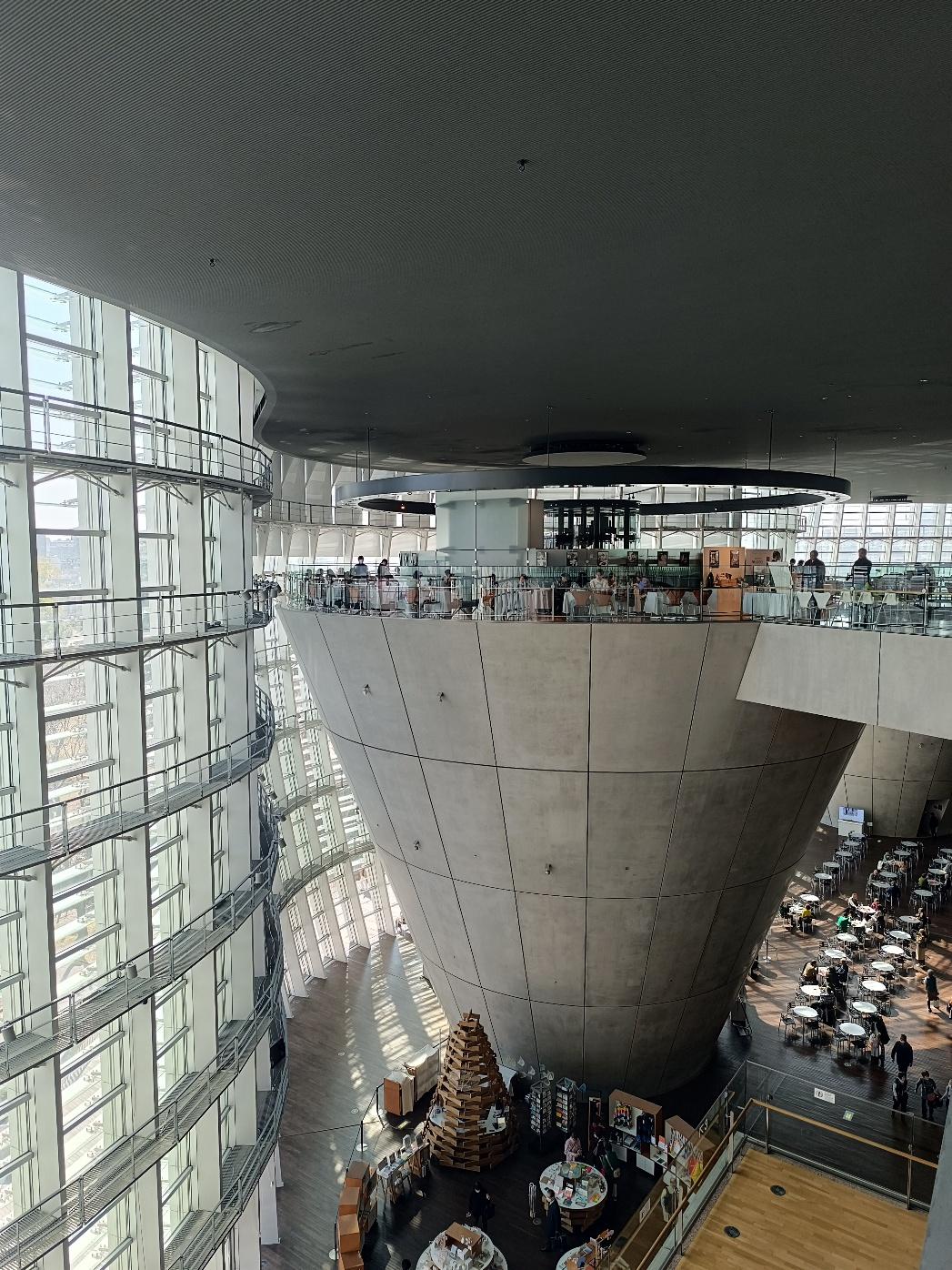 Il grande cono rovesciato in cemento nell'atrio del National Art Center di Tokyo, con il ristorante sulla sua sommità e la vetrata curva sulla sinistra